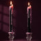 set of two black taper candles that drip red wax when lit