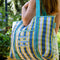 model carrying blue, white and yellow plaid large recycled plastic tote bag with ric rac detail and embroidered three fishies on the front pocket