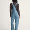 back view of model wearing stonewash relaxed fit overalls with multiple pockets and 'carpenter' type style