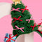 up close of green tulle christmas tree with colorful bows, gold star and stacked christmas presents