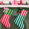 set of two striped stockings: dark green and lime green top with pink and red striped bottom and pink and red stripe top and dark green and baby blue striped bottom hanging from a mantle