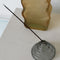 grey stacked glass incense holder with an incense inside on a table