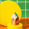 ceramic orange juice shaped ornament on yellow pedestal