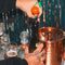 Hand holding the cherry wine topper to place into wine bottle