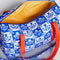 inside of yellow gingham lining of white and blue Scandinavian floral print with red strap and bow