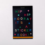 sticker book with black cover with colorful 'HIP HIP HOORAY IT'S A STICKER BOOK' across the front and gold elastic band