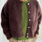 model wearing dark brown oversized cardigan with shell buttons and two front patch pockets 