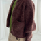 sideview of model wearing dark brown oversized cardigan with shell buttons and two front patch pockets 