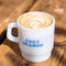 reverse side of white mug with snoopy in a large red puffer jacket and yellow beanie with a latte inside that says 'COZY SEASON'