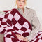 model with light pink and burgundy checkered blanket draped over their chest