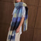 side view of model wearing thick scarf with various shades of blue checkers and fringe