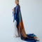 model wrapped with navy, light blue, orange and yellow checkered throw blanket with fringe