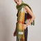 side view of model wearing thick scarf with orange, burnt red, and moss green print and fringe