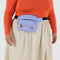 model wearing cornflower fanny pack with embroidered miffy and star print with black strap and zipper trim around their waist