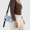 model carrying light blue small crescent bag with black embroidered ballet icon print and black strap