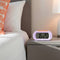 lavender digital alarm clock with orange trim on a bedside table