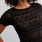 up close of model wearing black lace short sleeve top with leather pants
