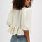 back view of model wearing jacquard blouse with puff sleeves, slight peplum hem, and black bow and buttons on the bust