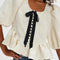model wearing jacquard blouse with puff sleeves, slight peplum hem, and black bow and buttons on the bust