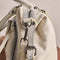 side view of mini washed beige leather purse with several zippered pockets, double handles and crossbody strap