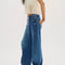 side view of model wearing low rise dark denim barrel jeans