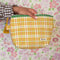 model holding yellow, burnt red and mint plaid quilted pouch with green print trim