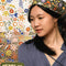 model wearing black square cotton bandana with colorful abstract floral print in their hair