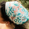 model wearing cream square bandana with dark teal green, blue, cream, red flowers
