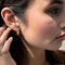 model wearing gold spike huggie hoops