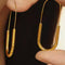 model wearing gold paperclip hoop earrings