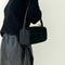 model carrying black nylon barrel handbag with leather buckle shoulder strap and trim