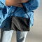 model holding black nylon barrel handbag with leather buckle shoulder strap and trim