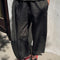 model wearing black pants with workmen patches down the front and inner drawstring