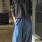 model wearing black pin-tucked blouse with button neck opening