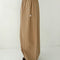 side view of model wearing khaki parachute pants with elastic waist and side pockets