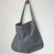 model carrying navy and white gingham rectangular bag hanging from a hook