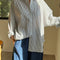 model wearing white relaxed fit button front shirt with side vents, collar and denim blue stripes