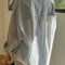 back view of model wearing white relaxed fit button front shirt with side vents, collar and denim blue stripes