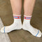 inside of model wearing white socks with red and blue stripes with red embroidered heart detail