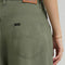up close of model wearing olive green slouch chino pants with pleated front