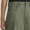up close of model wearing olive green slouch chino pants with pleated front