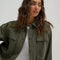 model wearing olive green cropped utility jacket with large patch pockets on the front