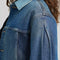 up close of model wearing patched denim chore jacket with a mix of light and dark wash denim and front patch pockets