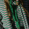 up close of model wearing kelly green and pink striped cardigan with gold bow buttons with matching bonnet and scarf