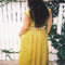 backview of model wearing chartreuse midi dress with white lace accents on the bust, two tie front and ruffle detail on the shoulders