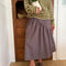 model wearing brown striped midi skirt with asymmetrical detail on the waist 