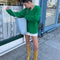 front view of model wearing green textured v-neck sweater and twill skirt