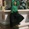 side view of model wearing green textured v-neck sweater and twill skirt