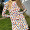 model wearing white cotton cardigan with red lettuce trim, red button front, and retro primary color floral print