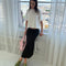 model wearing black crinkle midi skirt with shaped shell buttons on the top